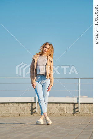 Stylish woman enjoying a sunny day at a waterfront promenade with blue sky Stylish woman enjoying a sunny day at a waterfront promenade with blue sky 130920081