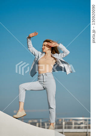 Dancer poses confidently against a clear blue sky at a vibrant outdoor location 130920090