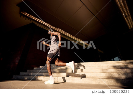Athlete Jogging on Sunlit Steps Near a Modern Urban Building 130920225