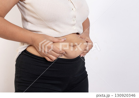 Overweight woman hand pinching excessive belly fat on gray background, Healthy concept Overweight woman hand pinching excessive belly fat on gray background, Healthy concept 130920346