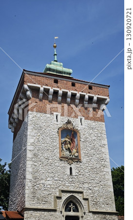 Historic stone tower with red brick top and decorative artwork under a clear blue sky. Concept of medieval architecture and cultural heritage tourism 130920721