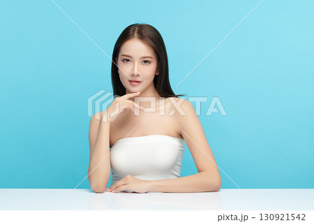 A beautiful young Asian woman with clean, fresh skin against a blue background. Skincare, facial treatment, cosmetology, beauty, and spa. An elegant portrait of an Asian woman. A beautiful young Asian woman with clean, fresh skin against a blue background. Skincare, facial treatment, cosmetology, beauty, and spa. An elegant portrait of an Asian woman. 130921542