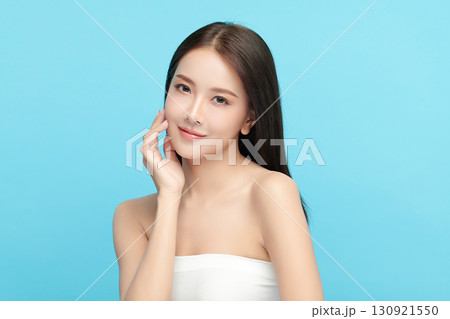 A beautiful young Asian woman with clean, fresh skin against a blue background. Skincare, facial treatment, cosmetology, beauty, and spa. An elegant portrait of an Asian woman. A beautiful young Asian woman with clean, fresh skin against a blue background. Skincare, facial treatment, cosmetology, beauty, and spa. An elegant portrait of an Asian woman. 130921550