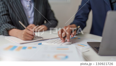 Financial Analysis. Business professionals collaborating on budget calculations using a calculator. 130921726