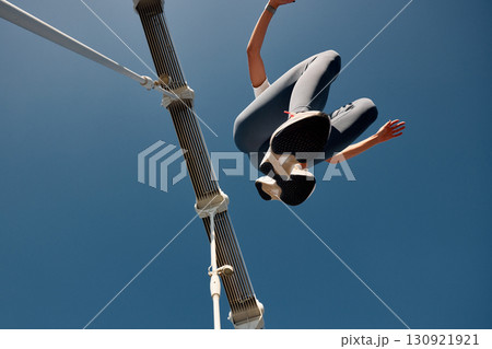 Low angle view of a person jumping high under a clear blue sky Low angle view of a person jumping high under a clear blue sky 130921921