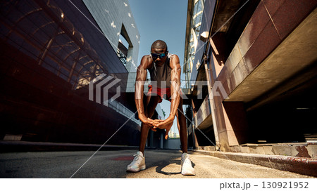 Athlete stretching outdoors in a modern urban city environment Athlete stretching outdoors in a modern urban city environment 130921952