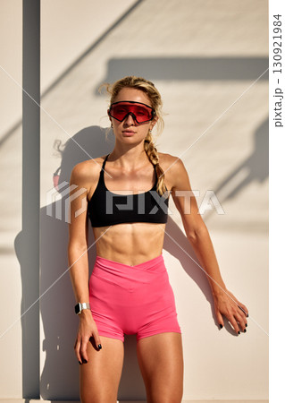 Athletic woman in sportswear posing outdoors with modern sunglasses and braided hair 130921984