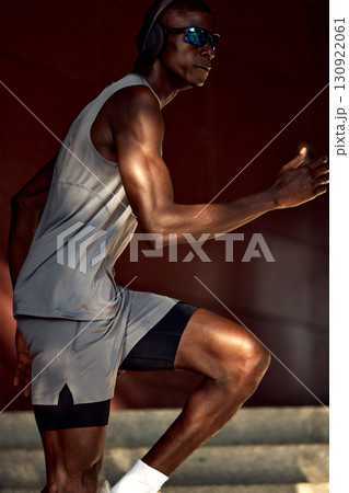 Athletic man running outdoors wearing headphones and sunglasses for fitness 130922061