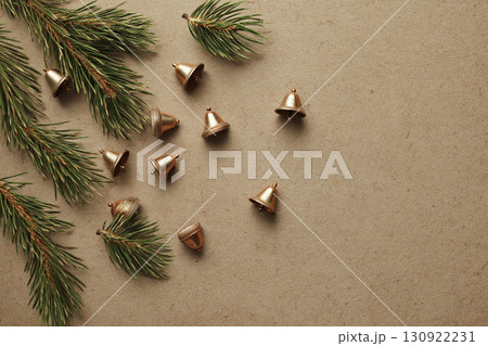 A flat lay of scattered small, generic bells and pine needles on a plain, textured background, creating a festive sound. 130922231