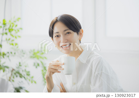 リビングでコーヒーを飲むミドルの女性 リビングでコーヒーを飲むミドルの女性 130923017