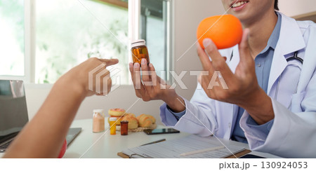 Medication and Nutrition. Doctor discussing health with patient, holding orange and medicine. Medication and Nutrition. Doctor discussing health with patient, holding orange and medicine. 130924053