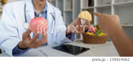 Dietary Choices. Doctor comparing healthy apple and pastry during patient consultation. Dietary Choices. Doctor comparing healthy apple and pastry during patient consultation. 130924062