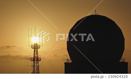 Malta: Golden sunset illuminating radio towers and a radar antenna, creating a striking silhouette against the colorful sky in Malta. Drone flight Malta: Golden sunset illuminating radio towers and a radar antenna, creating a striking silhouette against the colorful sky in Malta. Drone flight 130924320