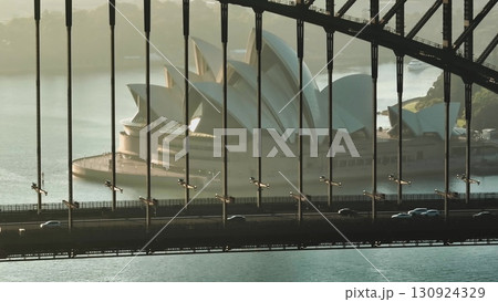 Australia, Sydney City: Sydney Harbour Bridge at sunrise, with Sydney Opera House framed between the bridge's girders. Cars driving traffic road. Modern architecture and urban transport in Australia 130924329
