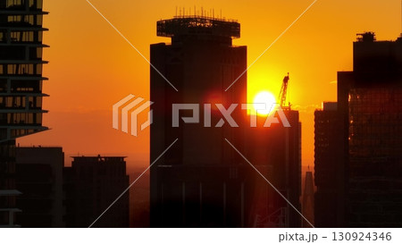 Australia, Sydney: Sydney's skyline buildings in sunset light, silhouette skyscrapers and construction cranes against a vibrant golden orange sky. Modern city architecture. Aerial view drone 130924346