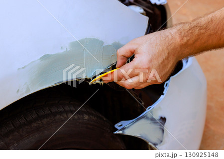 Hand applying body filler to car dent during repair at workshop on works day 130925148