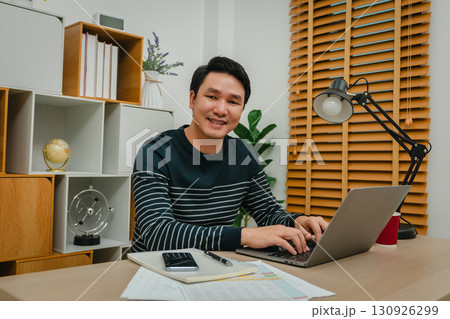 happy man working with laptop computer at home office 130926299