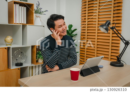 happy man using wireless earbuds to listening music and tablet at home office 130926310