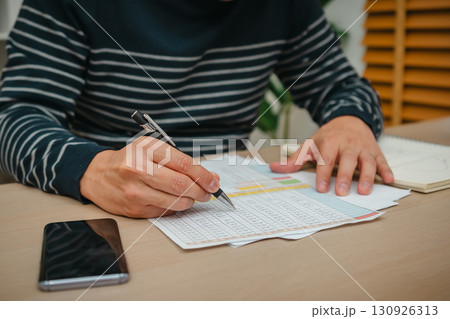 hand holding pen and wtiting document work at home office 130926313