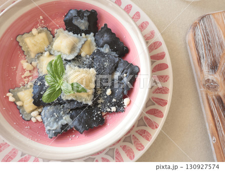 Cooked homemade ravioli with basil leaves and cheese on plate in kitchen. Healthy eating and organic products. Traditional food, Italy. Cooked homemade ravioli with basil leaves and cheese on plate in kitchen. Healthy eating and organic products. Traditional food, Italy. 130927574