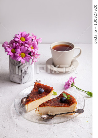Slices of Homemade Basque burnt cheesecake on a plate with blueberries and mint leaves on light background 130927920