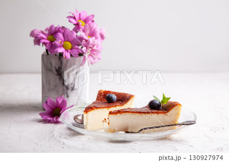 Slices of Homemade Basque burnt cheesecake on a plate with blueberries and mint leaves on light background 130927974