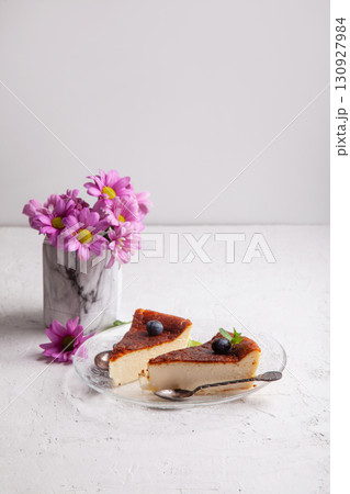 Slices of Homemade Basque burnt cheesecake on a plate with blueberries and mint leaves on light background Slices of Homemade Basque burnt cheesecake on a plate with blueberries and mint leaves on light background 130927984