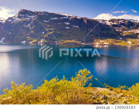 Panoramic view of the high mountain lake with dam. Lake Svartavatnet in the mountains in summer. Natural park in the municipality of Sauda. The beautiful nature of Norway Panoramic view of the high mountain lake with dam. Lake Svartavatnet in the mountains in summer. Natural park in the municipality of Sauda. The beautiful nature of Norway 130928163