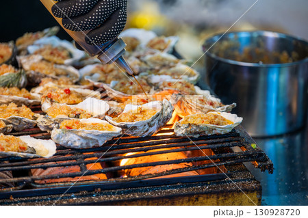 Grilling delicious oysters with spicy topping on street 130928720