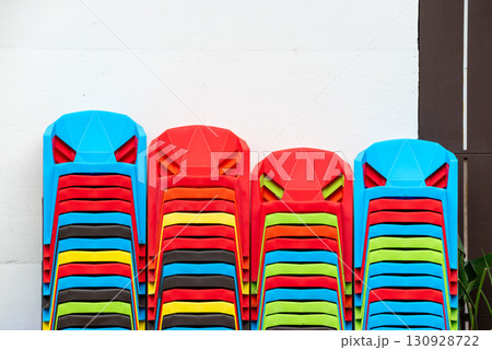 Colorful stacked plastic chairs in a alleyway reflect vibrant lo 130928722