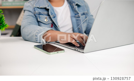 Man working on laptop with smartphone on desk, remote work and freelance lifestyle concept 130928757