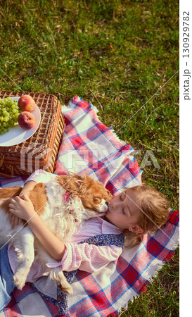Girl lying with dog on blanket at picnic in sunny meadow Girl lying with dog on blanket at picnic in sunny meadow 130929782