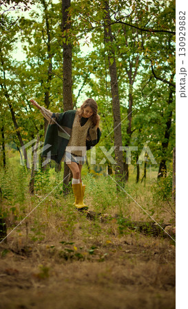 Woman balancing on forest path in autumn outfit and yellow boots 130929882
