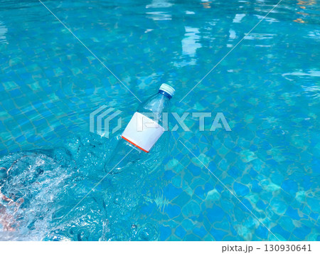 Plastic bottle floating on clear blue water, symbolizing pollution and environmental issues in aquatic environments. Plastic bottle floating on clear blue water, symbolizing pollution and environmental issues in aquatic environments. 130930641