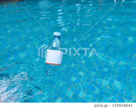 Plastic bottle floating on clear blue water, symbolizing pollution and environmental issues in aquatic environments. 130930642