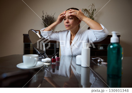 Woman Applying Facial Treatment While Sitting at Vanity Table at Home Woman Applying Facial Treatment While Sitting at Vanity Table at Home 130931348