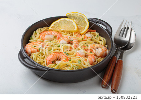 Delicious seafood pasta spaghetti with shrimps dish garnished with lemon and parsley angle view on white background Delicious seafood pasta spaghetti with shrimps dish garnished with lemon and parsley angle view on white background 130932223