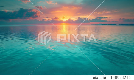 Sunset over the oceans, ocean shimmers with reflections of a pink and blue sunset, clouds scattered above, and a calm sea below 130933210