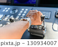 A close up view of a yacht or ship bridge with a captains hand operating the throttle controls. 130934007