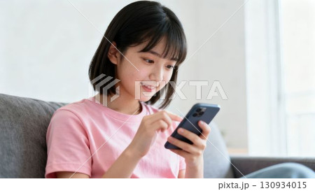 スマートフォンを見て微笑む若い女の子 130934015