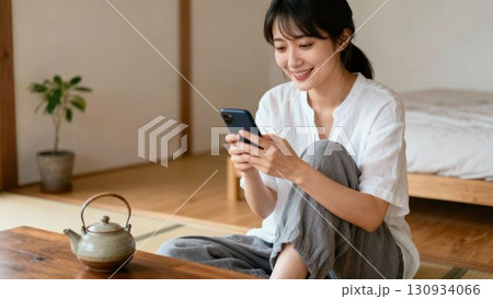 和室でスマートフォンを見てくつろぐ女性 130934066