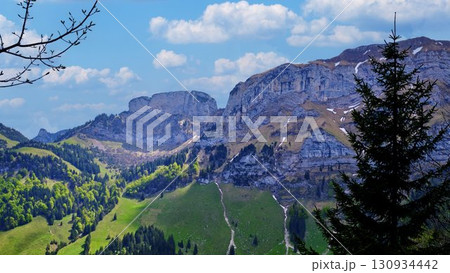 Stunning mountain landscape showcases rocky formations and lush greenery under a bright blue sky Stunning mountain landscape showcases rocky formations and lush greenery under a bright blue sky 130934442