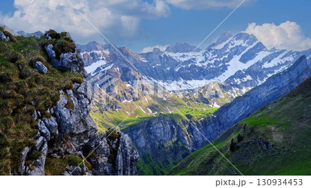 Majestic mountains rise above green valleys under a clear blue sky in a breathtaking alpine landscape Majestic mountains rise above green valleys under a clear blue sky in a breathtaking alpine landscape 130934453