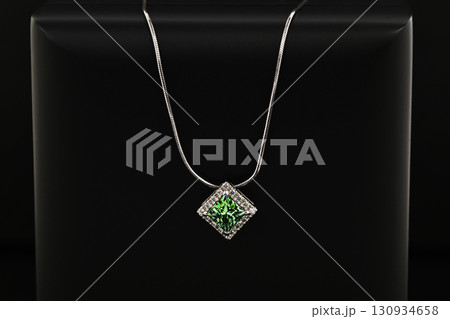 A green gemstone pendant is displayed on a black background 130934658