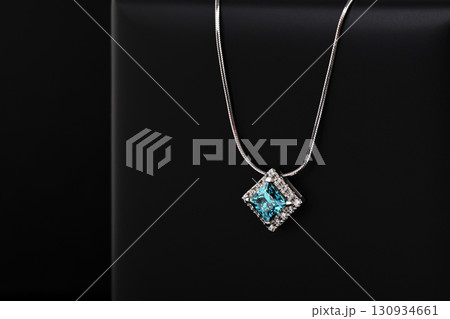 A blue and white necklace sits on a black surface 130934661