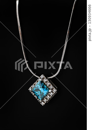 A blue gemstone necklace sits on a black surface A blue gemstone necklace sits on a black surface 130934666