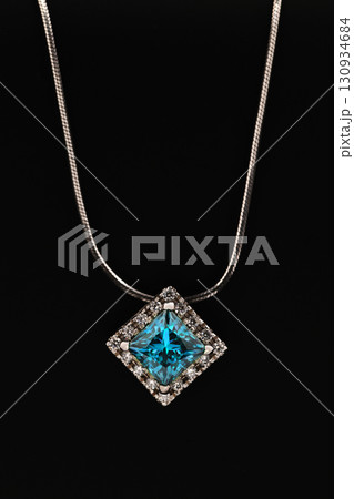 A blue diamond necklace sits on a black surface 130934684