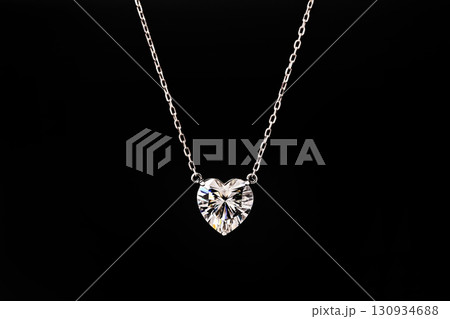 A necklace with a heart pendant is on a black record A necklace with a heart pendant is on a black record 130934688
