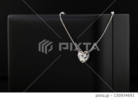 A necklace with a heart pendant is on a black record 130934691