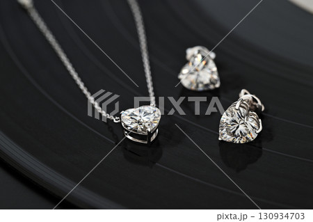 A necklace and earrings set made of diamonds are displayed on a black record A necklace and earrings set made of diamonds are displayed on a black record 130934703